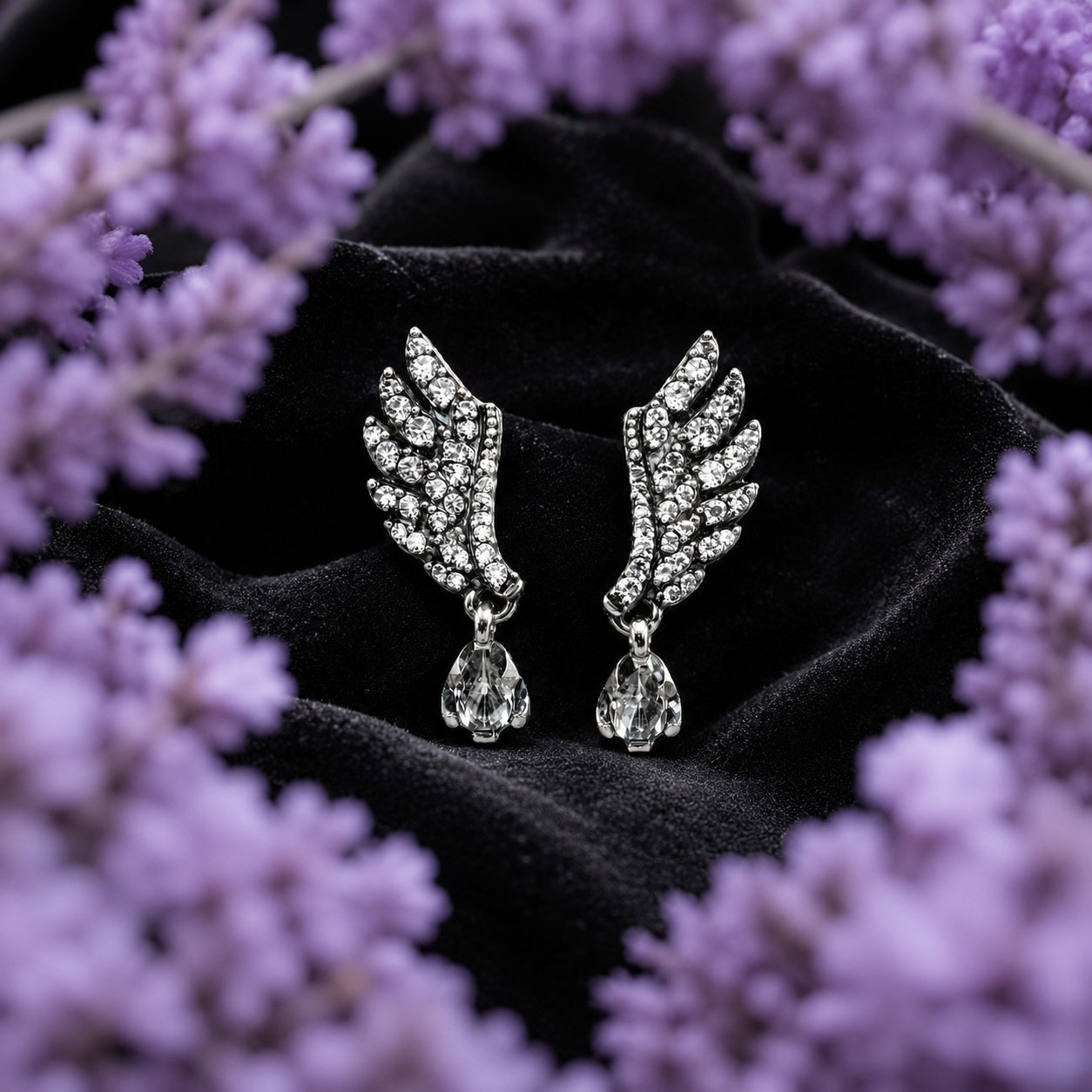Aretes Ala de Ángel de plata ley .925 de Joyería Colibrí sobre terciopelo negro, enmarcados por un halo de lavanda