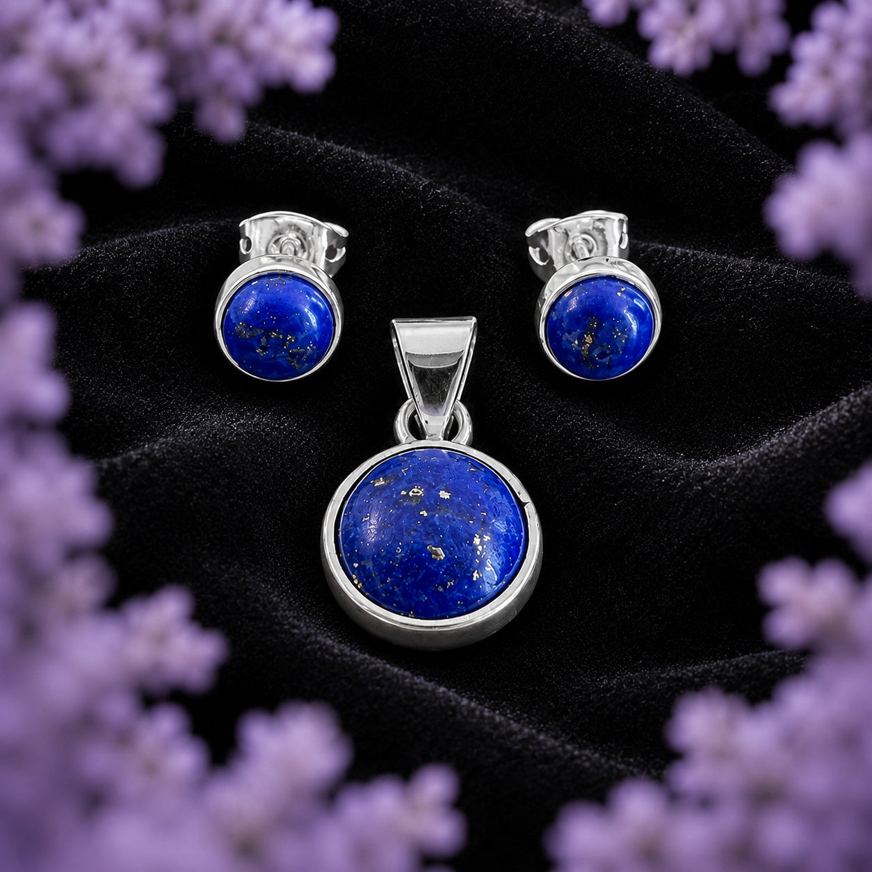 Coordinado de lapislázuli y plata ley .925 de Joyería Colibrí — dije y aretes a juego — sobre terciopelo negro, enmarcado por un halo de lavanda