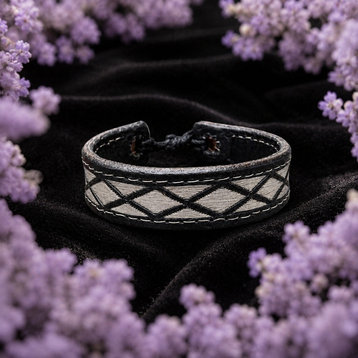 Pulsera de piel con hilo de plata ley .925 de Joyería Colibrí sobre terciopelo negro, enmarcada por un halo de lavanda