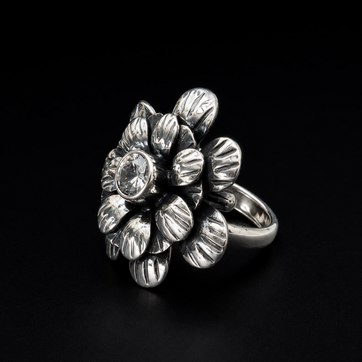 Anillo Flor con Circonia de plata ley .925 de canto sobre fondo negro, mostrando el volumen de la flor y el grosor de la banda